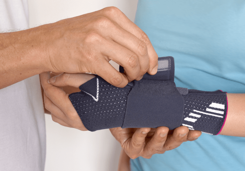 Court reporter fastening wrist brace on another court reporter