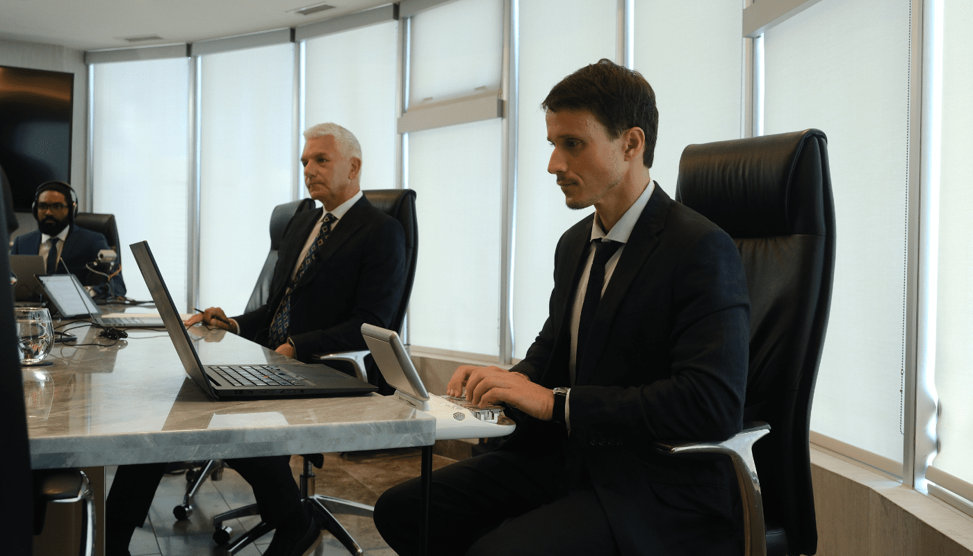Stenographic court reporter typing on stenotype machine with attorney and legal videographer sitting at table