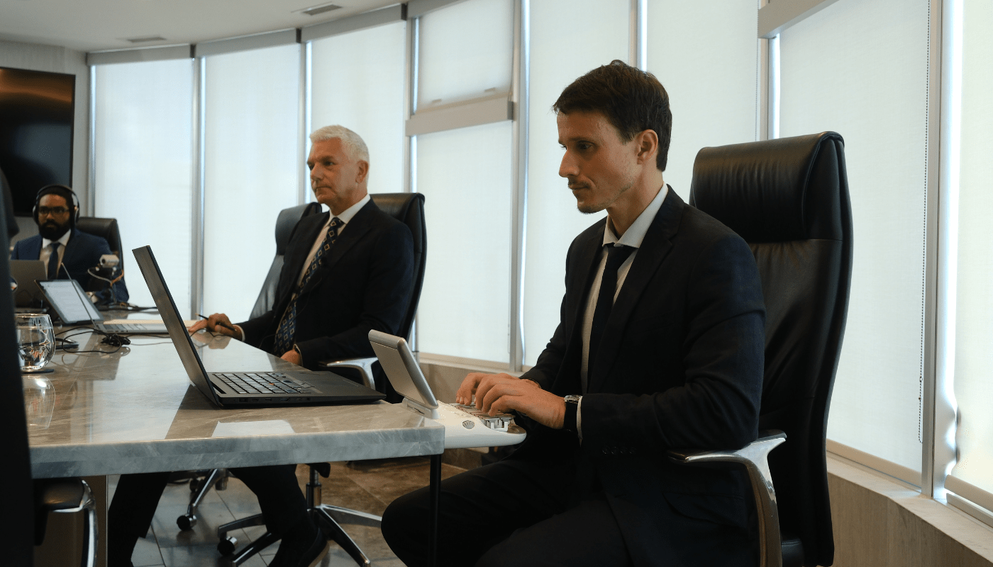 Stenographic court reporter typing on stenotype machine with attorney and legal videographer sitting at table